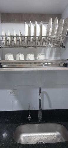 a kitchen counter with a sink and a shelf with dishes at Apartamento comodo a 15 minutos del Aeropuerto JMC in Rionegro