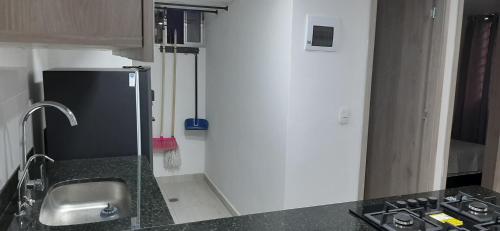a small kitchen with a sink and a refrigerator at Apartamento comodo a 15 minutos del Aeropuerto JMC in Rionegro