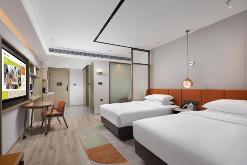a hotel room with two beds and a tv at Home2 Suites By Hilton Wuxi Huishan in Wuxi