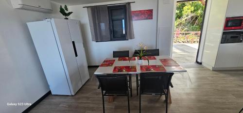 a kitchen with a table with chairs and a refrigerator at Villa Rosie in Sainte-Rose