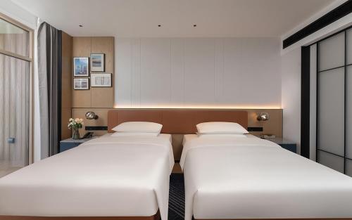 two beds in a hotel room with white beds at Four Points by Sheraton Dali, Erhai in Dali