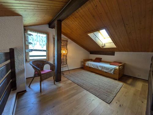 a bedroom with a bed and a chair in a attic at Chalet rénové 12 pers, 5 ch, parking, poêle, sud-ouest - FR-1-342-321 in Beaufort