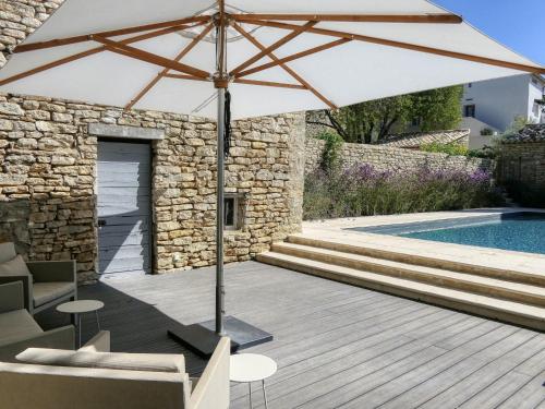 un parasol assis sur une terrasse à côté d'une piscine dans l'établissement Gîte authentique avec piscine privée, climatisation, Wi-Fi et animaux permis à Ménerbes - FR-1-708-84, à Ménerbes