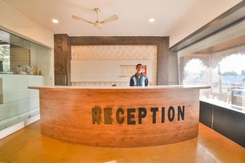 a man standing at a reception counter in a kitchen at Capital O Amit Palace in Bhilwara