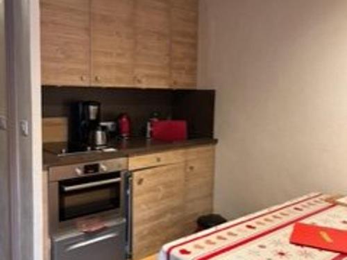 - une cuisine avec un four en acier inoxydable et des placards en bois dans l'établissement Studio 19m² calme avec balcon sud et parking privatif à Montriond - FR-1-573-133, à Montriond