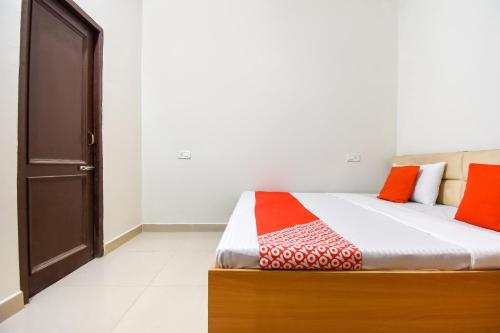 a bedroom with a bed with orange and red pillows at Hotel O Sabtera Homes in Kharar
