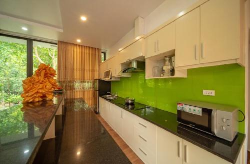 a kitchen with green walls and white cabinets at Đỗ Quyên Villa in Phúc Yên