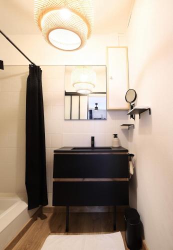 une salle de bain avec un lavabo noir et un miroir dans l'établissement Appartement hyper centre avec balcon, à Clermont-Ferrand