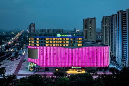 a building is lit up in pink in a city at Holiday Inn Express Binzhou City Center by IHG in Binzhou