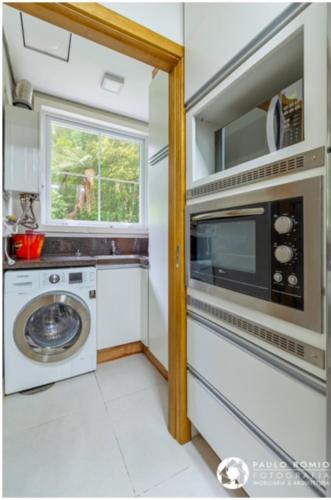 a kitchen with a microwave and a washing machine at Apartamento Homeland 305 in Gramado
