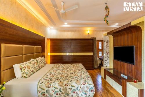 a bedroom with a bed and a flat screen tv at Udaikot by VEO - Part of StayVista in Udaipur