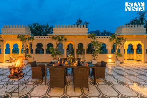 a patio with a table and chairs and a fireplace at Udaikot by VEO - Part of StayVista in Udaipur