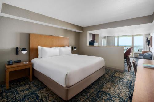 a hotel room with a large bed and a desk at Four Points by Sheraton Destin - Fort Walton Beach in Fort Walton Beach