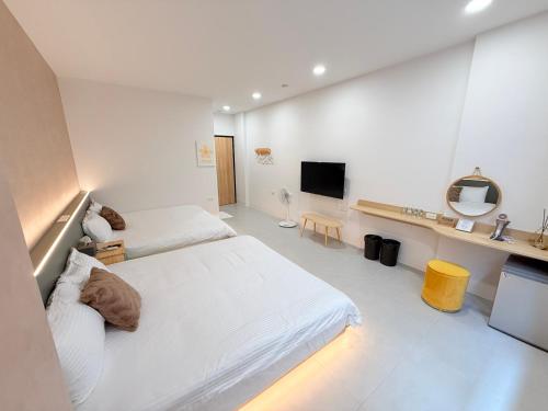 a white room with two beds and a television at 東港民宿 - 如你所院 Tourist Vacation B&B in Donggang
