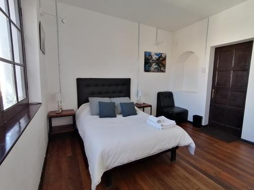 a bedroom with a large white bed with blue pillows at El Museo Hotel Boutique in La Paz