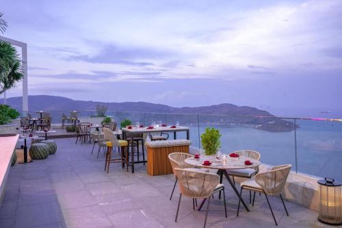 a patio with tables and chairs and a view of the ocean at TMS Quy Nhơn Sea View in Quy Nhon