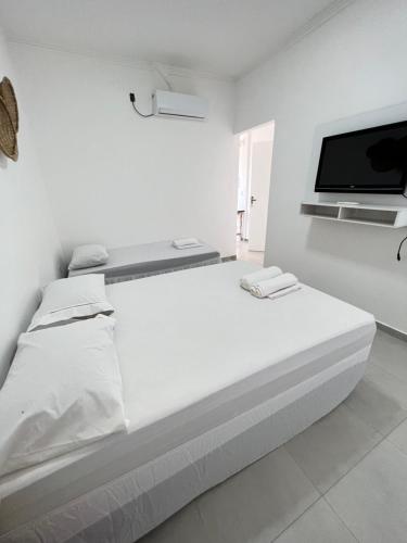 a white room with a bed and a flat screen tv at Pousada Balanço do Mar in Prado