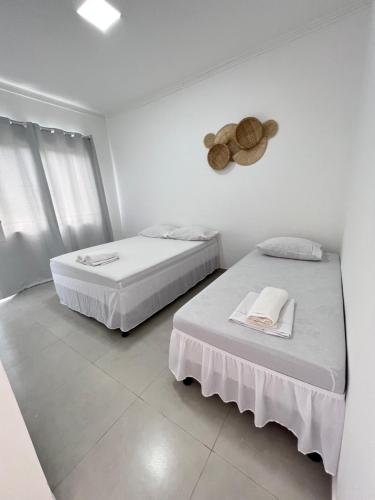 two beds in a room with white walls at Pousada Balanço do Mar in Prado