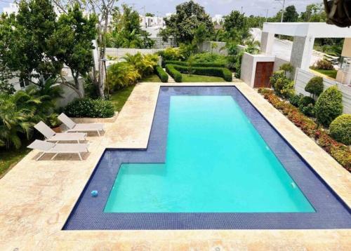 a swimming pool in the middle of a yard with chairs and trees at Luxury villa in punta cana with private pool in Punta Cana