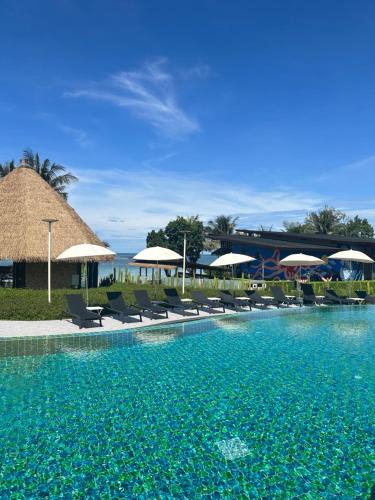 ein Resortpool mit Stühlen und Sonnenschirmen in der Unterkunft Kai Bae Beach Resort Koh Chang in Ko Chang
