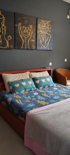 a bedroom with a bed with paintings on the wall at Coco Lux Studio Grand Baie in Grand Baie