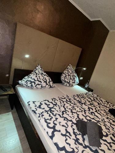 a bed with black and white sheets and pillows at Hotel Am Markt in Eschweiler