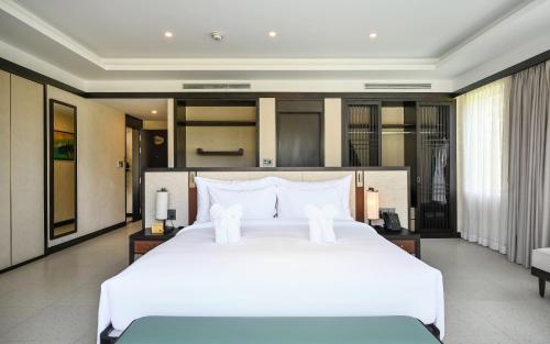 a large white bed in a hotel room at Emerald Ho Tram Resort in Ho Tram