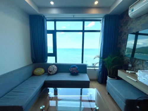 - un salon avec un canapé bleu offrant une vue sur l'océan dans l'établissement Beachfront Hon Chong Holtel & Apartment, à Nha Trang