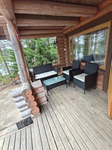 a porch of a log cabin with chairs and tables at Kalliorinteen Mökit Ruskapirtti in Töysä