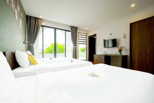two white beds in a room with a window at Hoi An Tháng 1 Villa in Hoi An