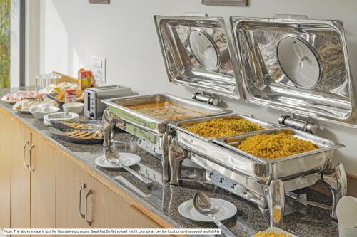 a kitchen counter with several trays of food at Treebo Kashvijoy, 7 Km From Kamakhya Temple in Guwahati