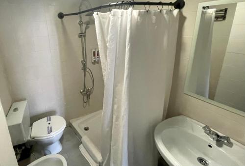 a bathroom with a shower curtain and a toilet and a sink at Itinere Rooms in Granada