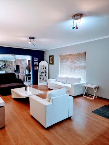 a living room with two white couches and a table at 3 bedroom garden house in Tableview in Table View