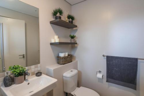 a bathroom with a toilet and a sink and a mirror at The Millennial Cosy stay in Durban