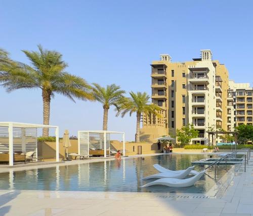 a swimming pool with palm trees and a building at Ultra Luxury Flat with Amazing Pool Near to Burj in Dubai