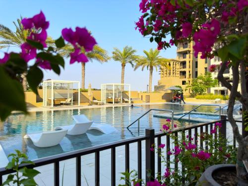 a swimming pool with chairs and palm trees in a resort at Ultra Luxury Flat with Amazing Pool Near to Burj in Dubai