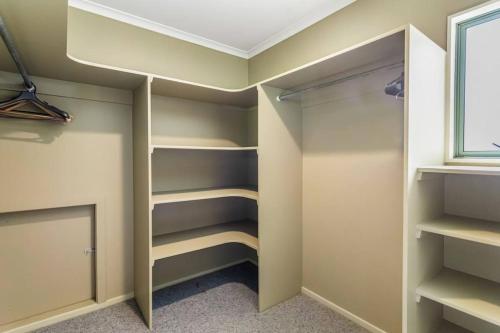a walk in closet with shelves and a window at Charming Oasis, Your Cozy Retreat Awaits in Auckland