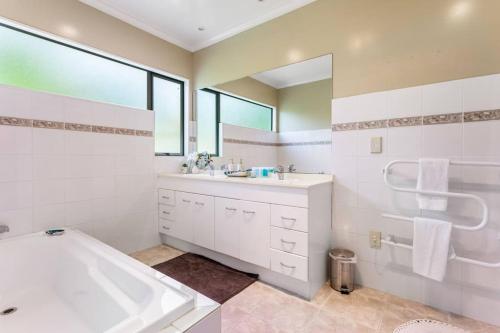 a white bathroom with a tub and a sink at Charming Oasis, Your Cozy Retreat Awaits in Auckland