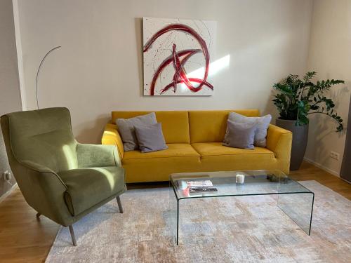 a yellow couch and a chair in a living room at Esprit-Apart-Hotel in Baden-Baden
