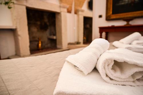 un rollo de toallas blancas en una cama en Il Voltone - Vivi Salento, en Copertino