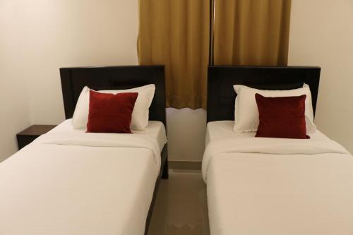 two beds with red pillows sitting next to each other at Vibha by Sri Lakshmi Homes in Chennai