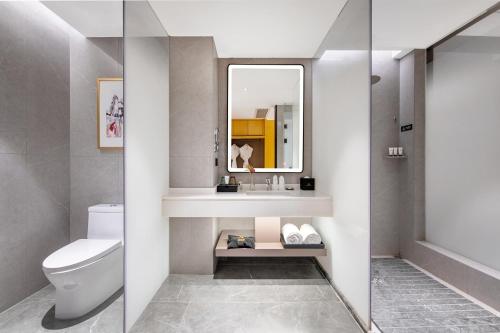 a bathroom with a toilet and a sink and a mirror at Guangzhou Southern Airlines Pearl Airport Hotel- Free shuttle bus to airport in Guangzhou