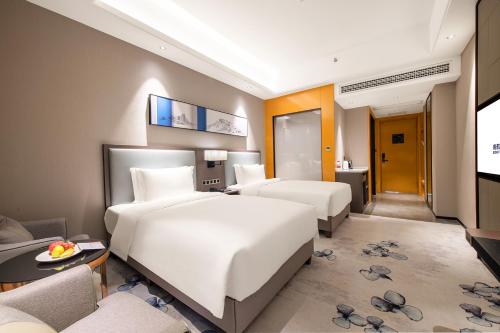 a hotel room with two beds and a couch at Guangzhou Southern Airlines Pearl Airport Hotel- Free shuttle bus to airport in Guangzhou