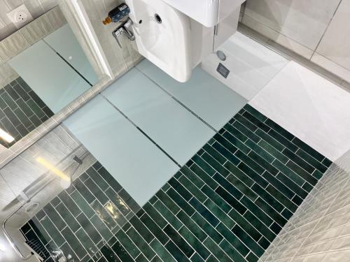La salle de bains est revêtue de carrelage vert et blanc. dans l'établissement Studio idéalement placé, à Paris