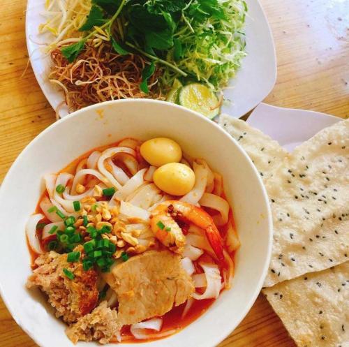 a bowl of food with noodles and vegetables on a table at Hoi An Tháng 1 Villa in Hoi An