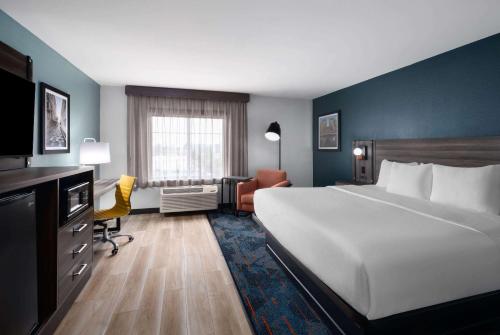 a hotel room with a large bed and a chair at La Quinta by Wyndham Greensboro NC in Greensboro