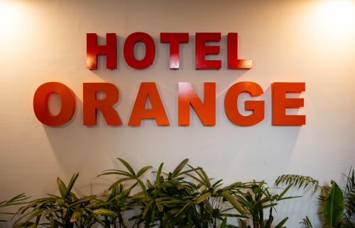 a hotel orange sign on a wall with plants at Hotel Orange in Bhubaneshwar
