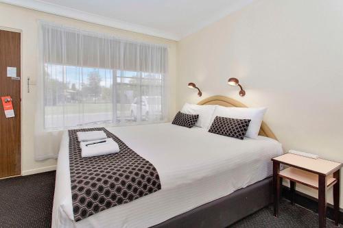 a bedroom with a large white bed with a window at Econo Lodge Savannah Park Tamworth in Tamworth