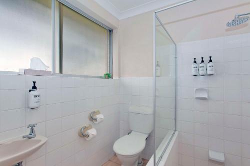 a white bathroom with a toilet and a sink at Econo Lodge Savannah Park Tamworth in Tamworth