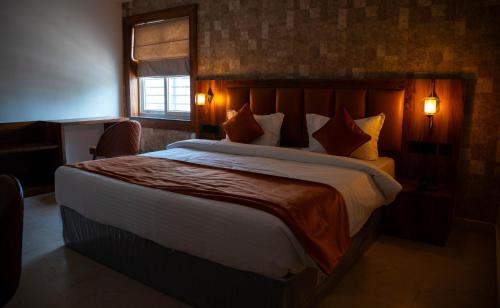 a bedroom with a large bed and a window at Hotel Orange in Bhubaneshwar